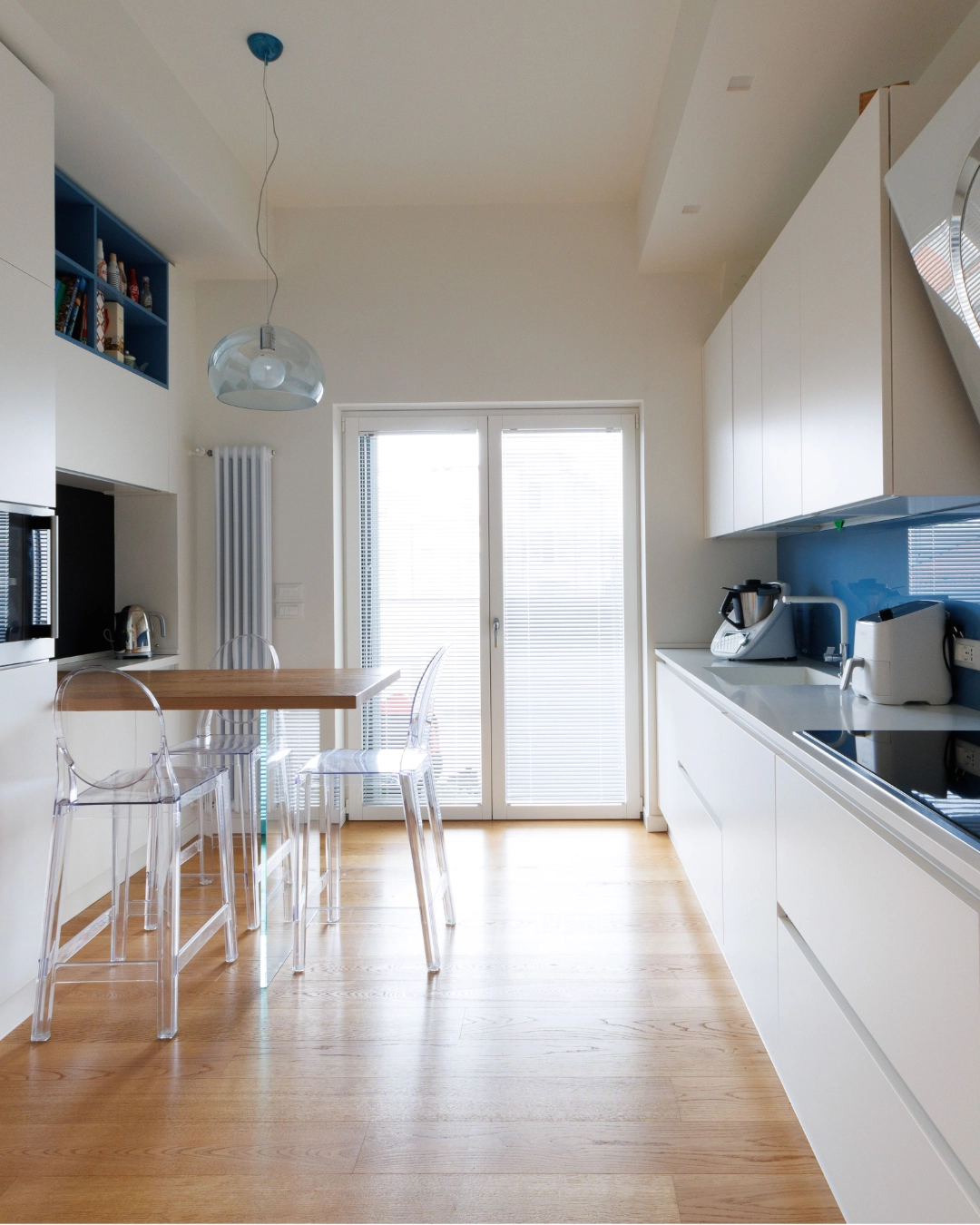 Cucina luminosa con sedie Ghost e paraschizzi azzurro